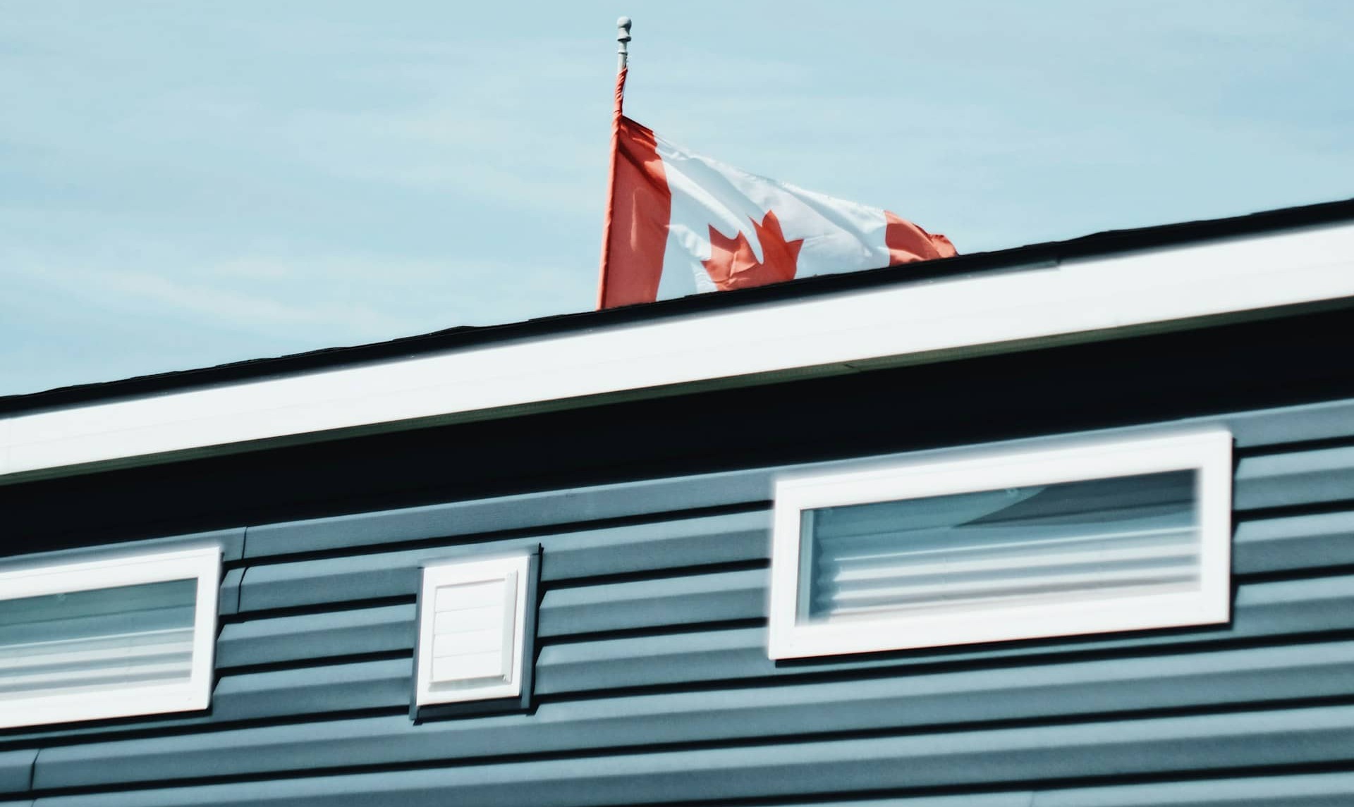 Canadian flag waving in the wind with a clear blue sky in the background